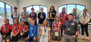 2024 SEDC Regional Spelling Bee participants. Back row, L to R: Travis Max Seegmiller, Iron; Grant Pearson, Iron; Harrison Francom, Iron; Hayes Holyoak, Millard; Savannah Paul, Washington; Audrey Ayala, Washington; Kaydee Ure, Beaver; Melody Williams, Beaver. Front row, L to R: Samantha Hart, Kane; Blake Hansen, Kane; Liv Glazier, Kane; Landry Holyoak, Millard; Jens Allen, Millard; Ellie Blackner, Beaver; Lily Burnett, Valley Academy; Brandt Hawkins, Valley Academy. Not pictured: Evan Chiu, Valley Academy and Kennedy Bolke, Washington.